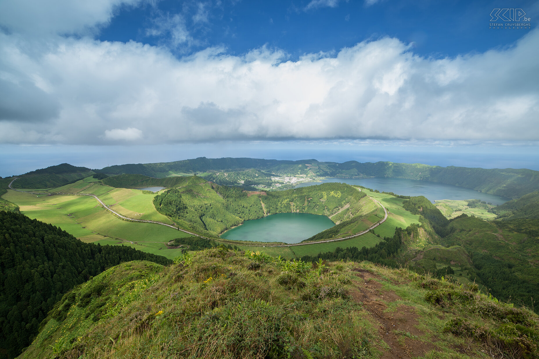 Sete Cidades - Miradouro da Boca do Inferno Het meest bekende uitzichtpunt over de kratermeren van Sete Cidades is Miradouro da Boca do Inferno. Achteraan liggen Lagoa Azul (blauwe meer) en het Lagua Verde (groene meer).  Het hoger liggende kratermeer is Lagoa de Santiago. De krater zou rond 1440 zijn ontstaan door een enorme eruptie die hier heeft plaatsgevonden. Zeevaarders die voor de kolonisatie langs São Miguel vaarden, beweerden dat er aan weerszijden een hoge berg was. Enkele jaren later, met de komst van de Portugezen, was de bergtop op het westelijke deel verdwenen. Stefan Cruysberghs